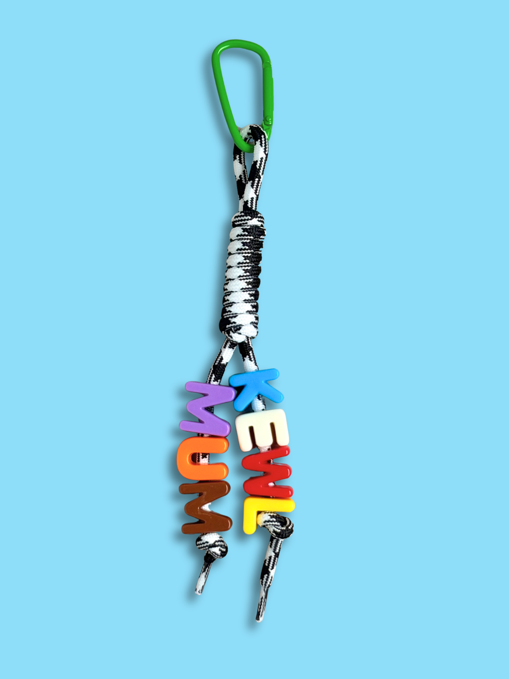 Custom statement bag charm with letter beads spelling KEWL MUM in blue, white, red, yellow, purple, orange, and brown, threaded across two strands of a black and white houndstooth knotted cord with a green carabiner clip, on a blue background. Made by Bugalugs in Melbourne. 