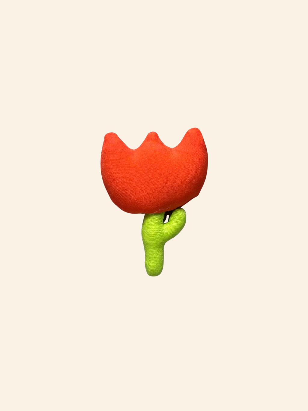 Puffy fabric tulip flower with orange red top and green stem on a cream background